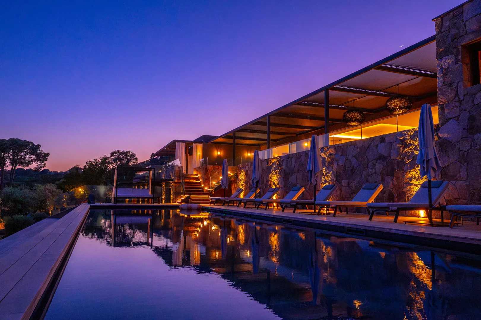 Piscine chauffée de l'Hôtel Villa Padulaccia au crépuscule, terrasses éclairées qui se reflètent dans l'eau