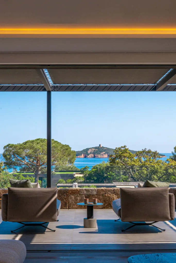 Deux fauteuils tournés vers la mer sous la pergola de l'Hôtel Villa Padulaccia, tour de l'île de Pinarellu au loin